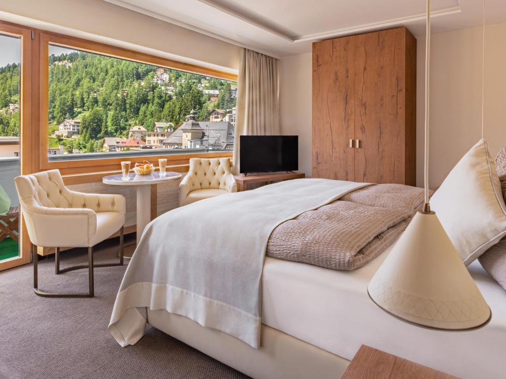 a bedroom with a large bed and a large window at Hotel Arte in St. Moritz