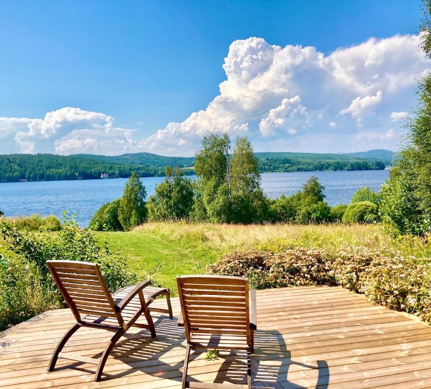 two chairs sitting on a wooden deck next to a lake at Hemsö Hideaway in Kojbacken
