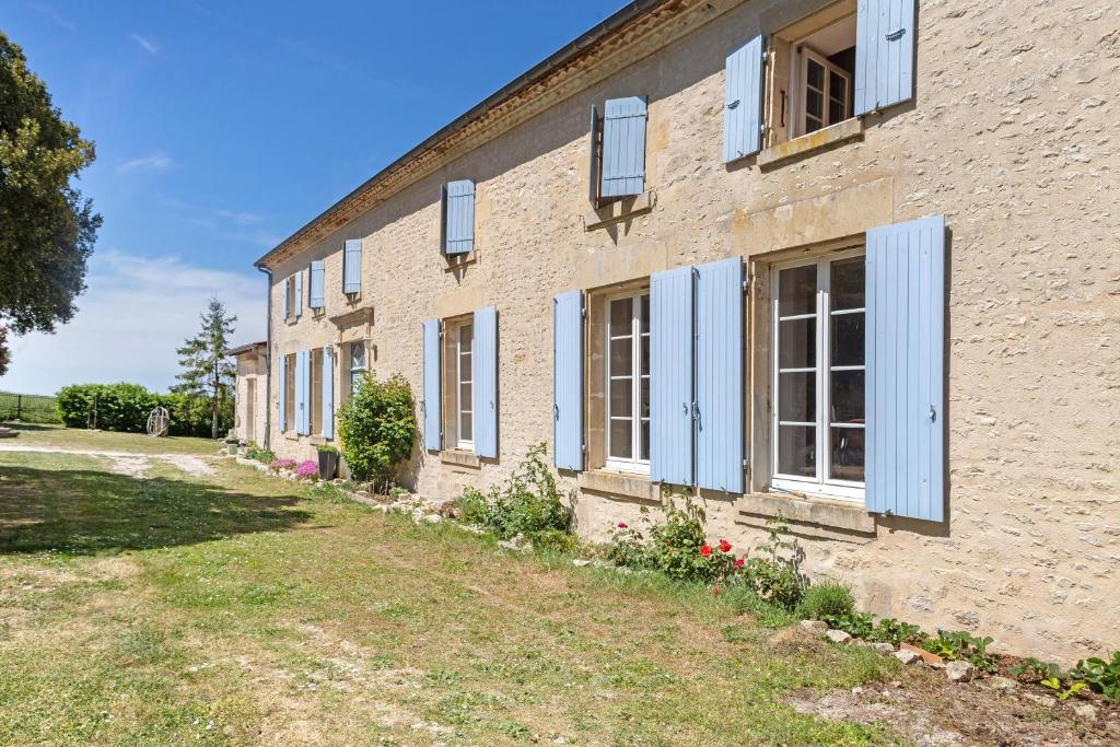 a brick building with blue shutters on it at Chambres en Charente Maritime in Loiré-sur-Nie
