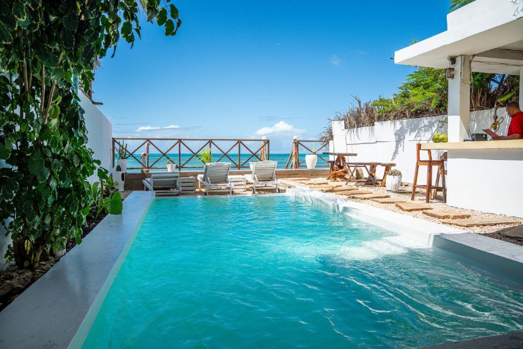 a swimming pool with chairs and the ocean in the background at ZAN Ocean View Hotel in Jambiani