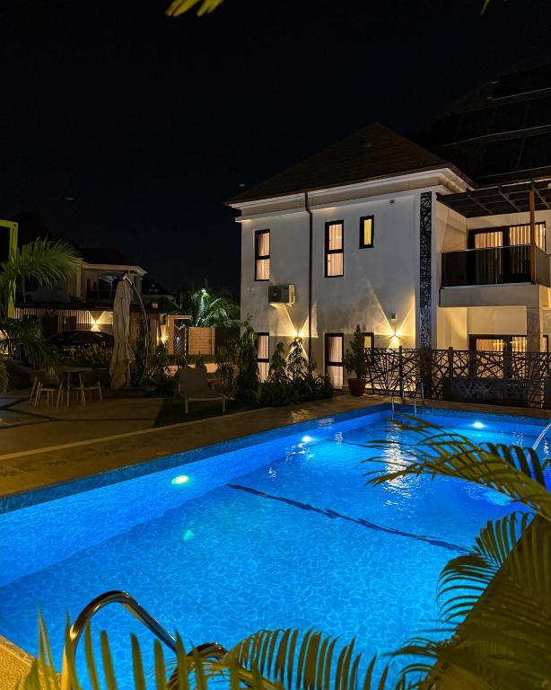 a swimming pool in front of a house at night at ASFARO Apartments in Abuja