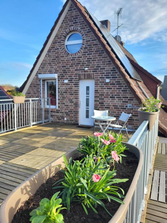 a small brick house with a deck and flowers at Gemütliche Wohnung mit großer Dachterrasse in Röhrsen