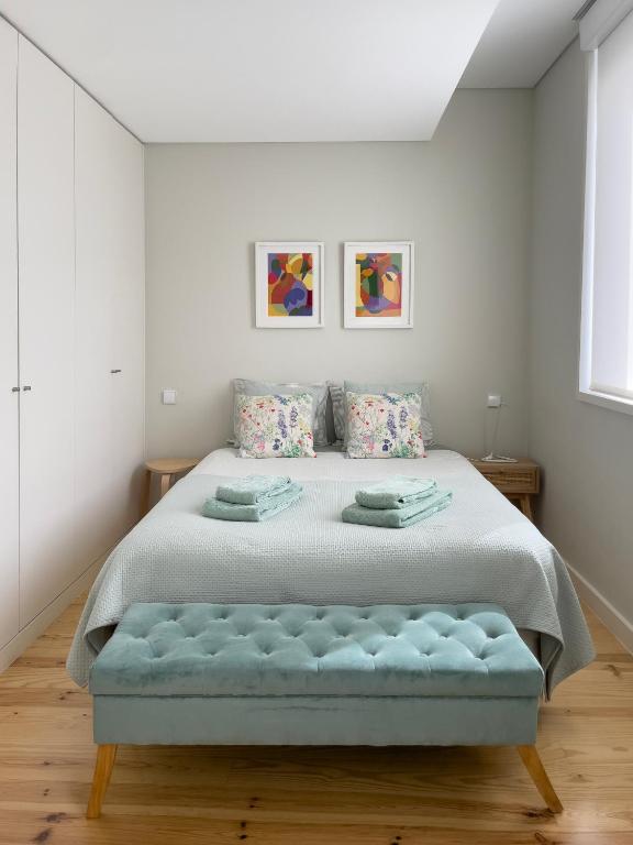 a white bedroom with a large bed with a blue bench at Allegro Patio House in Porto