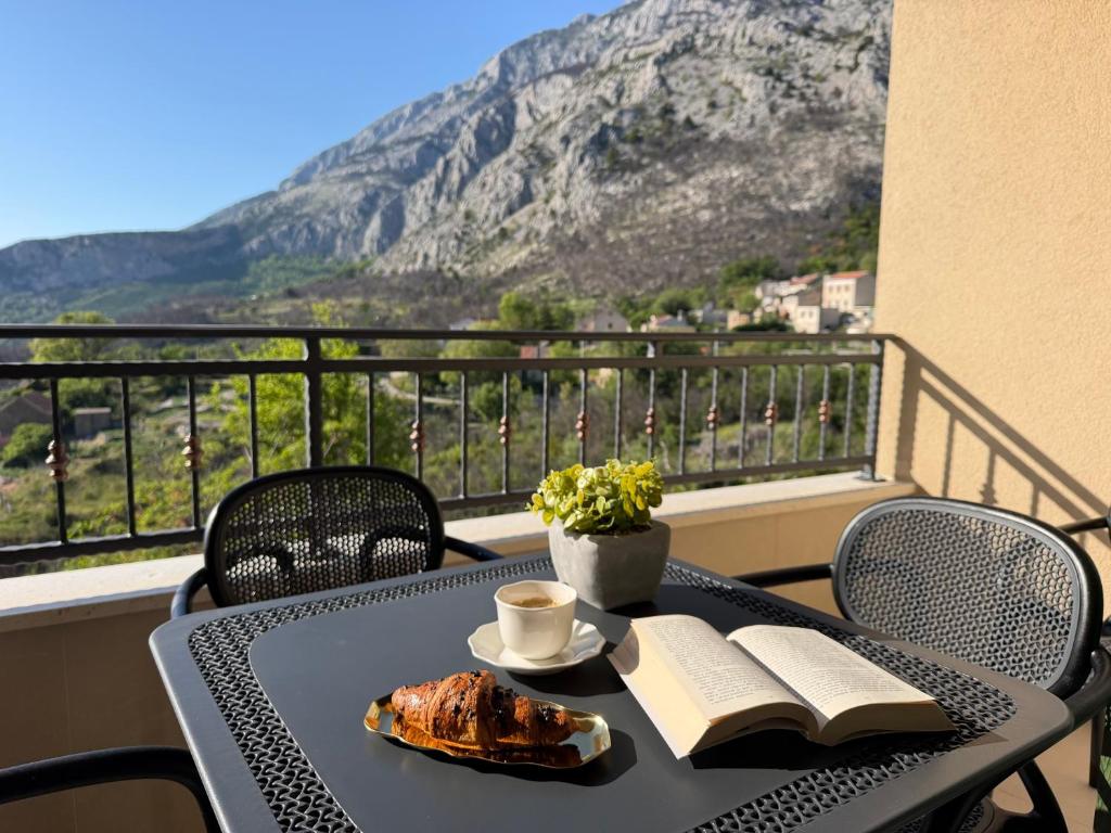 a table with a book and a cup of coffee on a balcony at Holiday Home Nada in Tučepi
