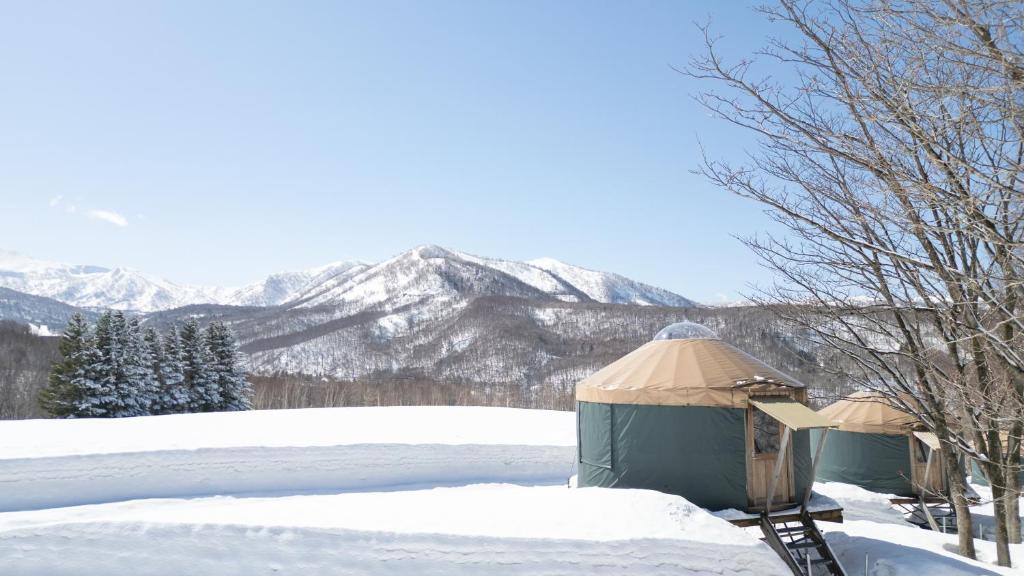 a yurt in the snow with mountains in the background at The Yurts at Margo's Garden, Kiroro in Shiribeshi