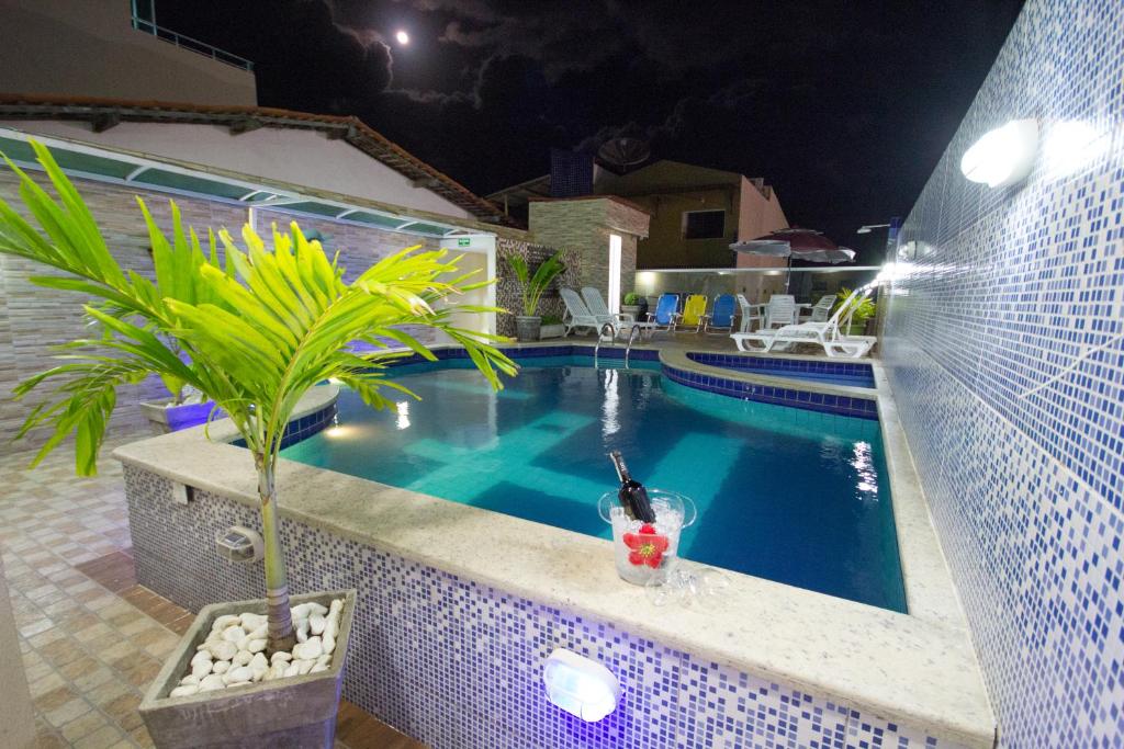 una piscina con una bebida y una palmera al lado en Pousada Maragolfinho en Maragogi