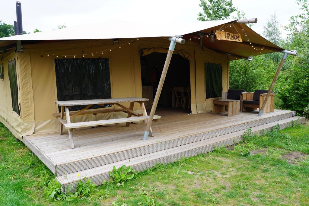 a tent with a wooden deck in a field at F1 Group Stay Close to Track Parking Grumpy in Amblève