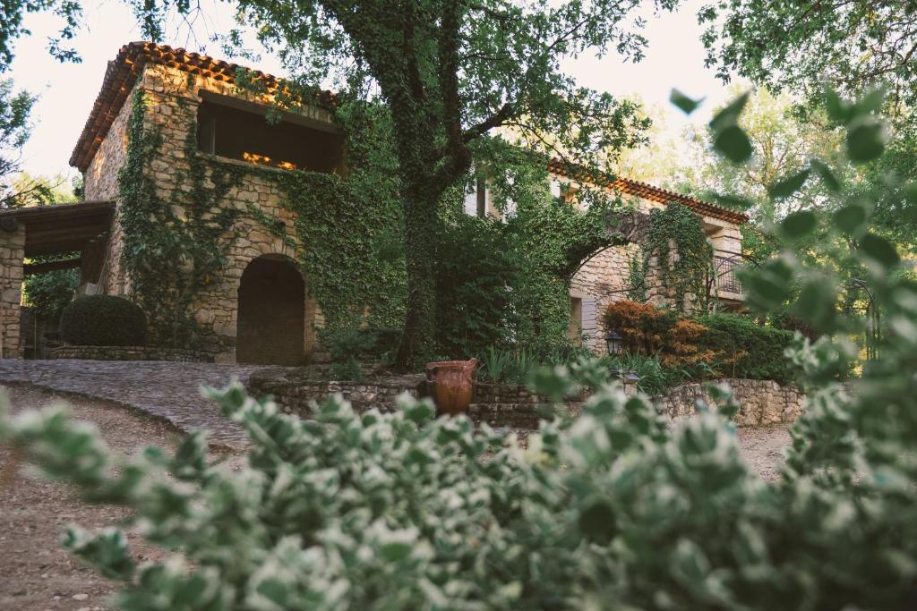 a building covered in ivy with a tree at Hôtel Le Rocher des Abeilles in Saint-Martin-de-Castillon