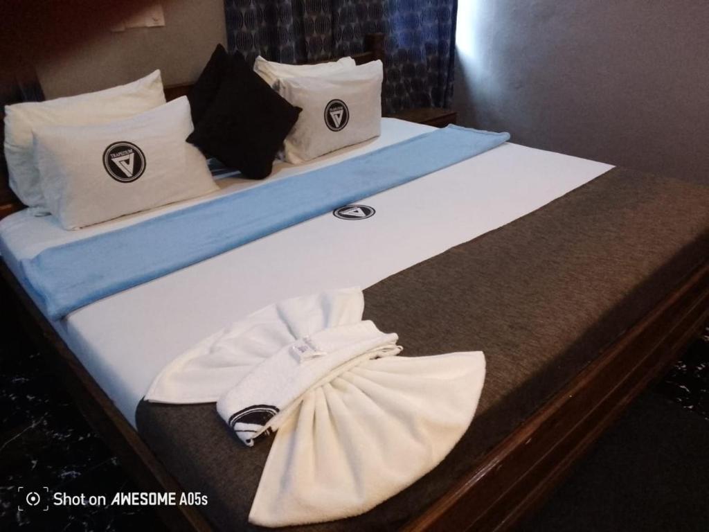 two beds in a hotel room with towels on them at Trapezium Lodge in Amasaman