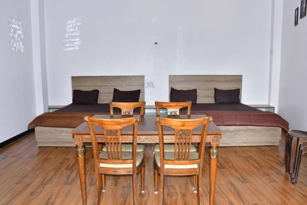 a dining room table with four chairs in front of a bed at Zeeenu Abode Yercaud by GD in Yercaud