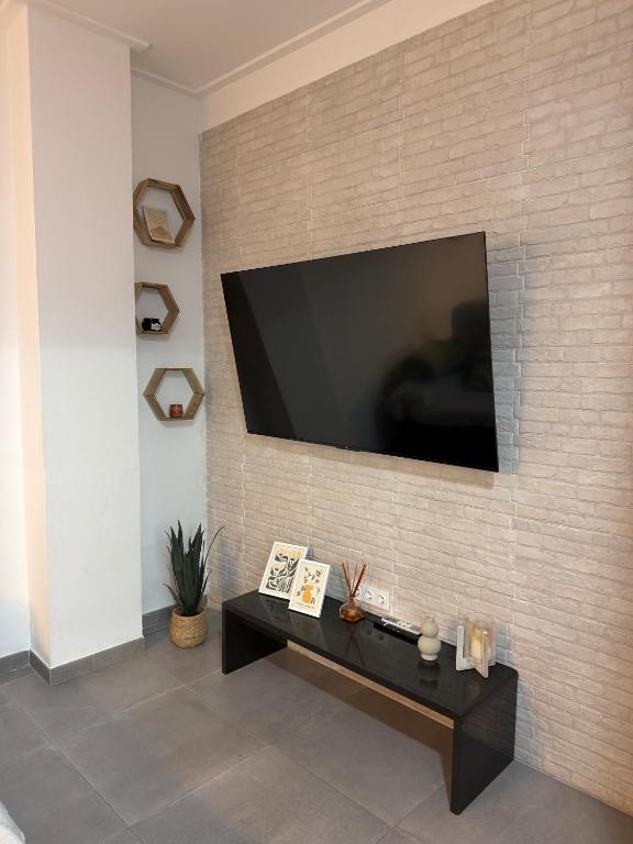 a living room with a television on a brick wall at Loft el Baix - Cullera in Cullera