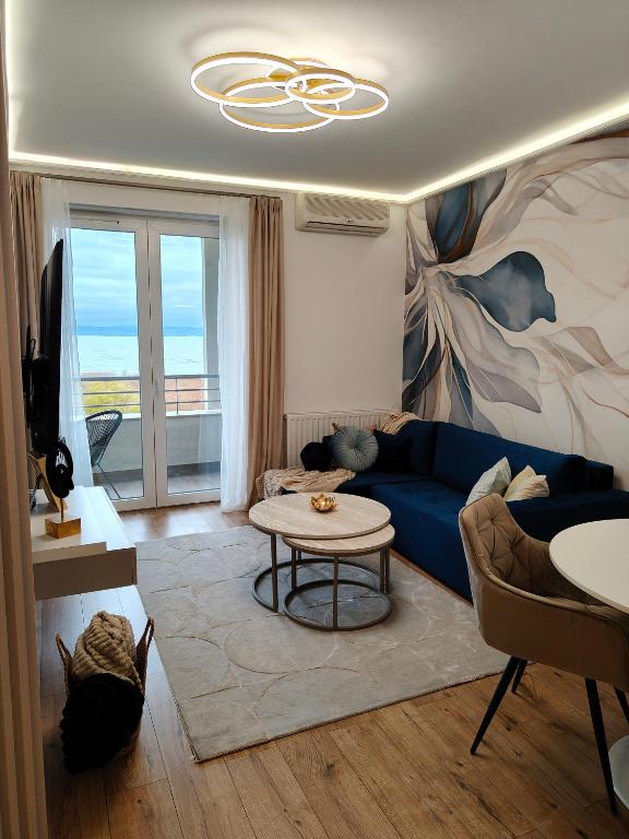 a living room with a blue couch and a table at Enidor Wellness Apartman in Siófok