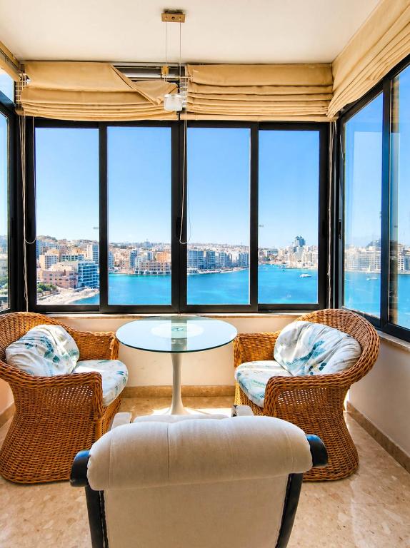a living room with a table and chairs and windows at The Horizon - Sea View 8 in Sliema