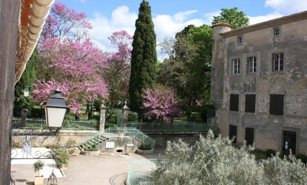a garden with pink trees and a building at Les Chambres Cast'elles in Malves