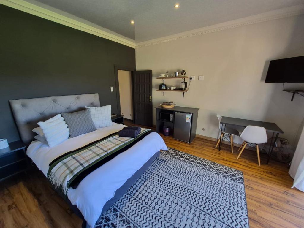 a bedroom with a large bed and a desk at Toekoms Inn in Aliwal North