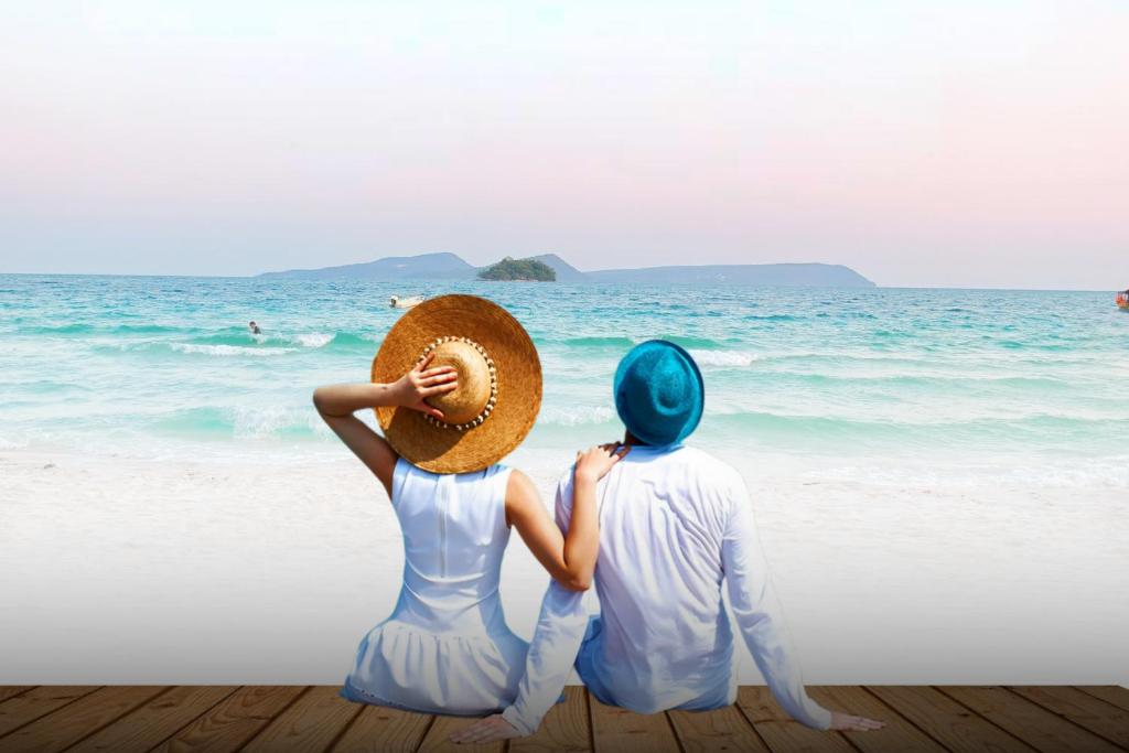 a man and woman sitting on the beach looking at the ocean at Royal C Resort in Koh Rong Island