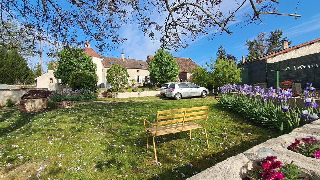 a wooden bench sitting in a yard with flowers at Dans colombier proche de Vichy parking privé in Vichy