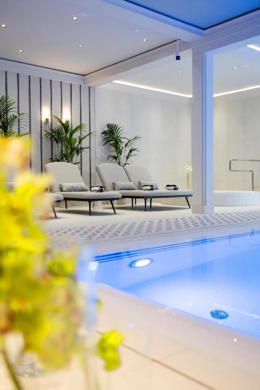 a swimming pool in a living room with chairs at Dwór Prezydencki Boutique Hotel & SPA in Tarnów