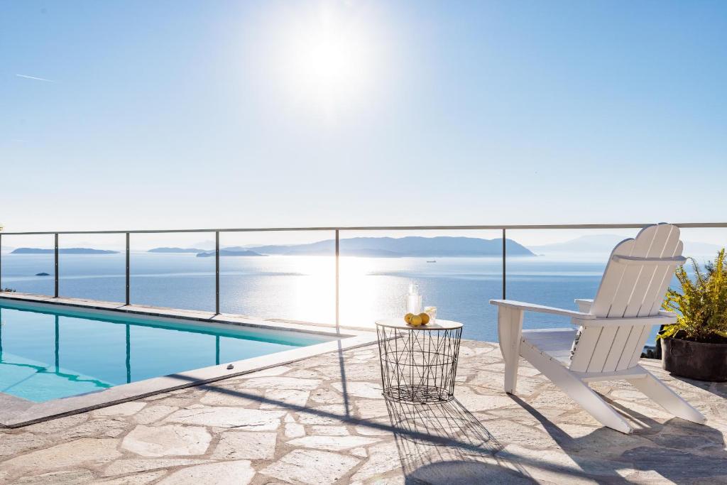a balcony with a chair and a swimming pool at Archodiko Palio Klima - Infinite Blue Elegance in Neo Klima