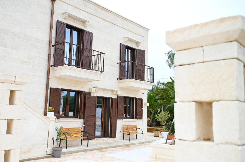 a white building with black windows and benches at Casa Macchiosa in Torre Canne