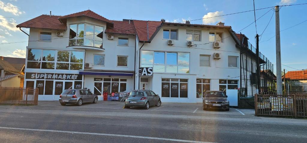 a white building with three cars parked in a parking lot at Apartments AS Dubrave in Dubrave Gornje
