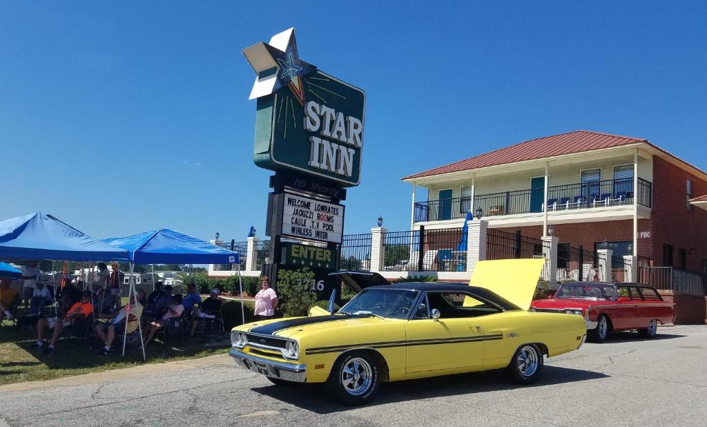 un coche amarillo estacionado frente a un motel estrella en Star Inn Biloxi en Biloxi