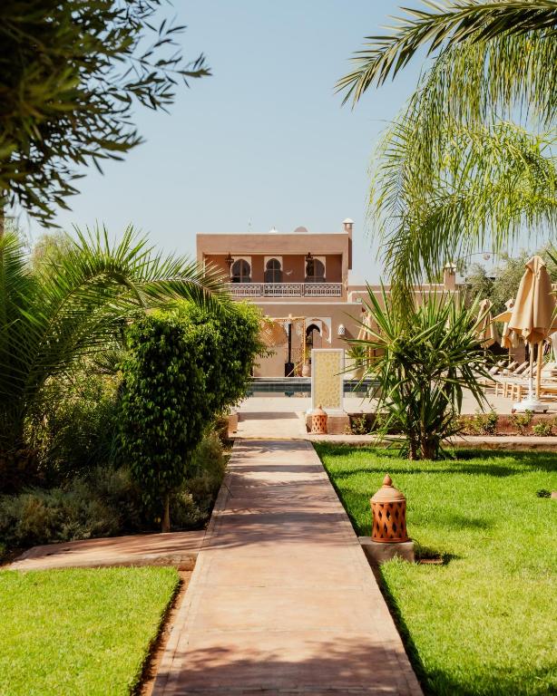 a walkway in front of a house with palm trees at Les Villas du Douar in Azib Oulad Lâdem
