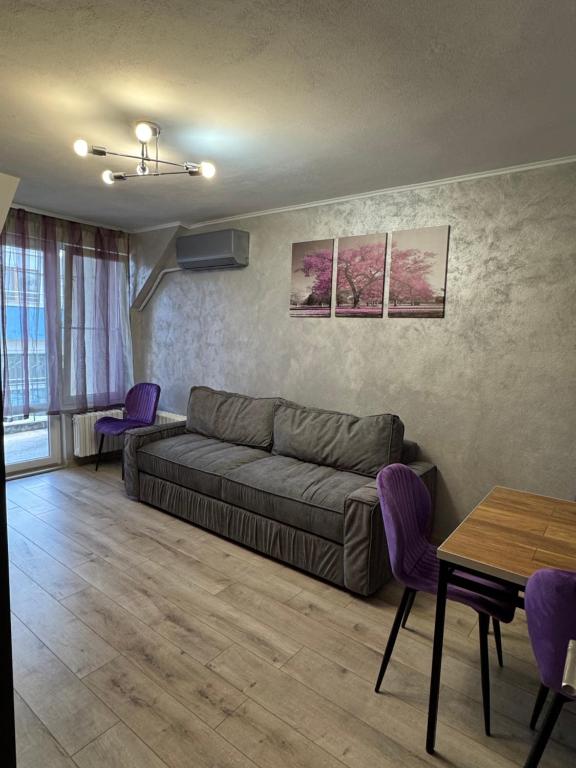 a living room with a couch and tables and purple chairs at Aneva home in Ruse