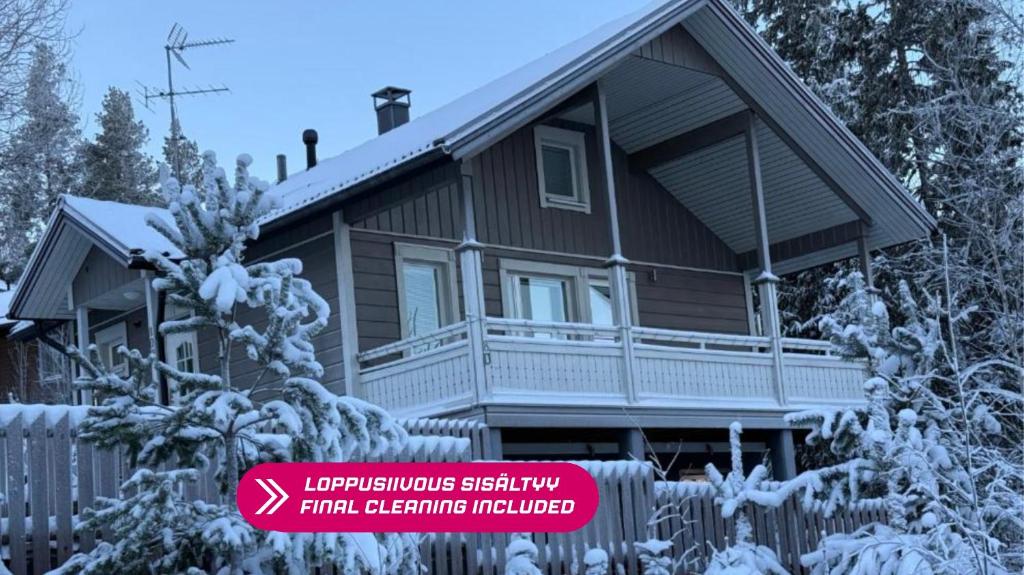 a house covered in snow with a sign in front at Villa IRIS 4, Himos in Jämsä