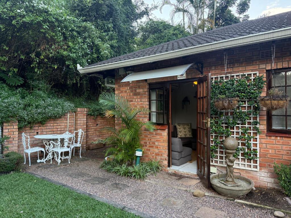 a brick house with a table and chairs in a yard at Tranquil Gardens in Pietermaritzburg