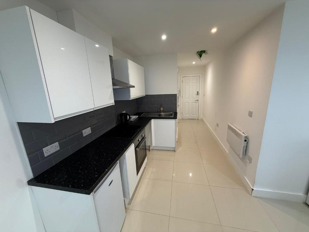 a kitchen with white cabinets and black counter tops at Radstock Road - Room 2 in Southampton