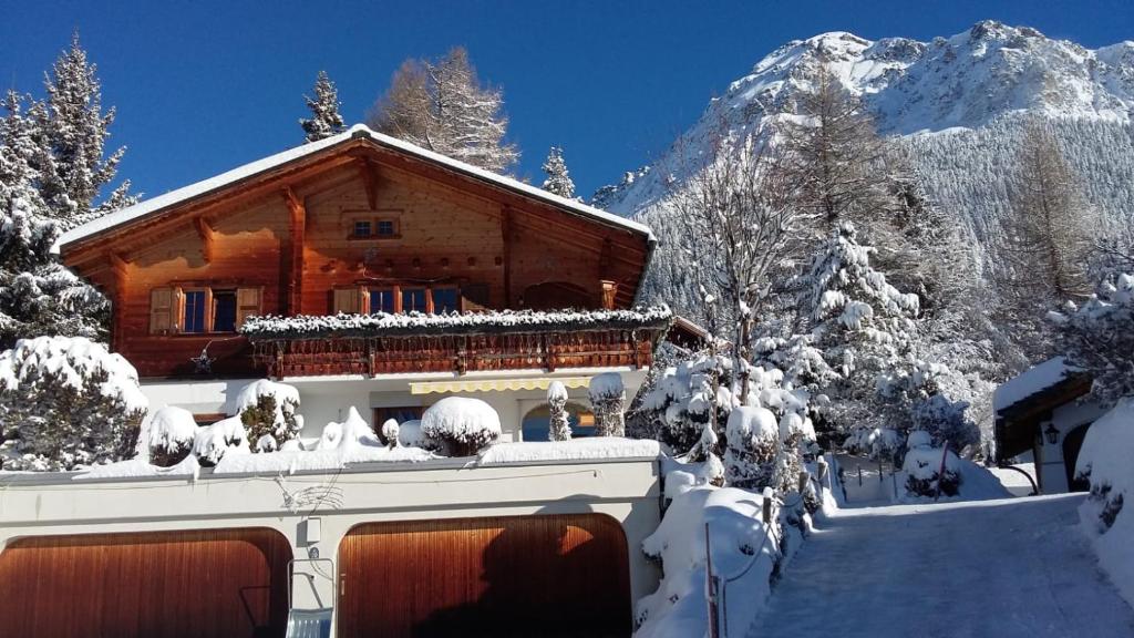 a log cabin in the snow in front of a mountain at Gemütliche 3 Zimmer Wohnung in Lenzerheide in Lenzerheide