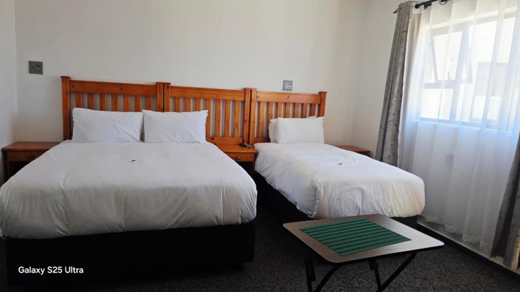 a bedroom with two beds and a window and a table at MOHALALITOE B and B in Maseru