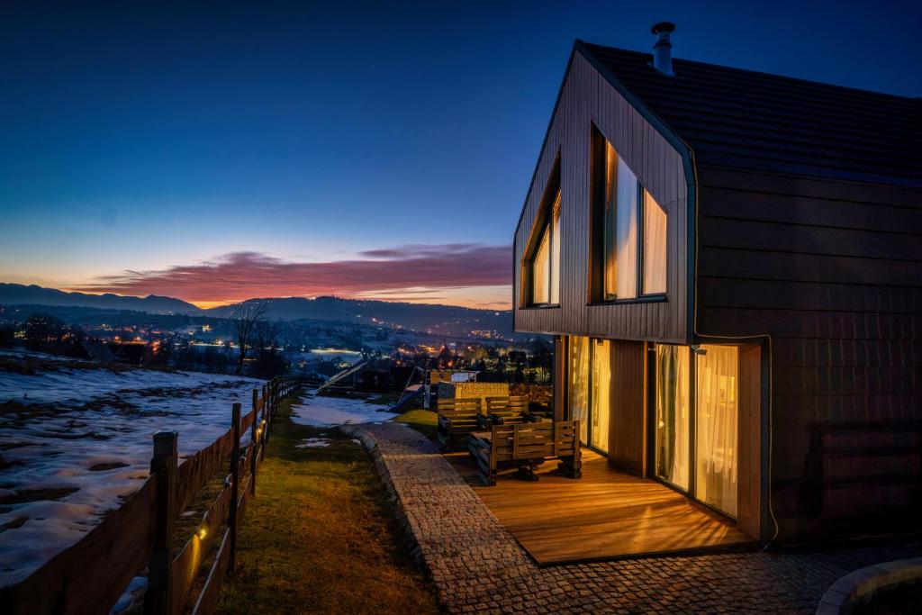 a house with a wooden deck with a sunset in the background at Góralski Dom - Osada Gawlaki in Zakopane