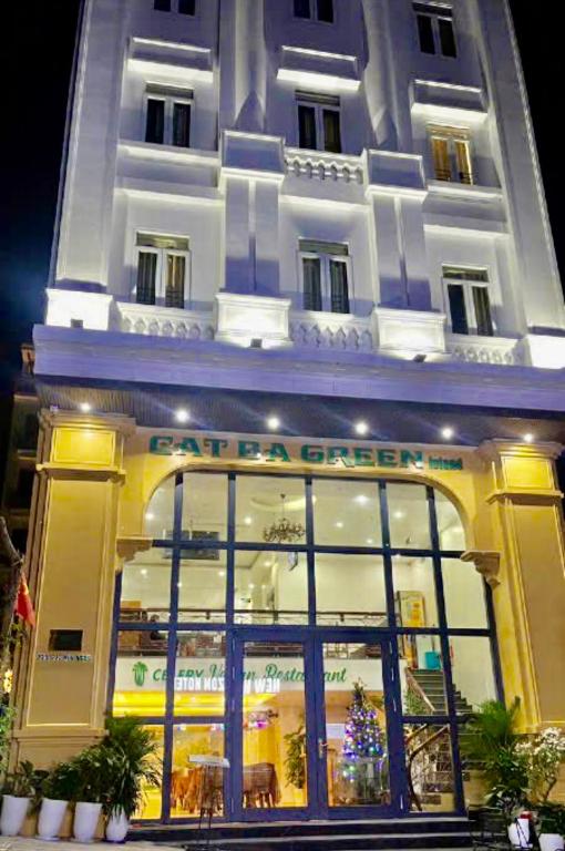 a large white building with a store window at night at Cat Ba Green Hotel in Cat Ba