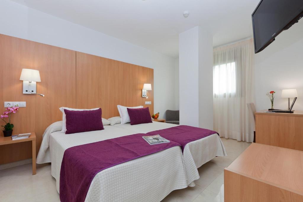 a hotel room with a large bed with purple sheets at Hotel Verol in Las Palmas de Gran Canaria