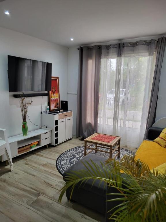 a living room with a couch and a flat screen tv at Hibiscus holiday in Capesterre-Belle-Eau