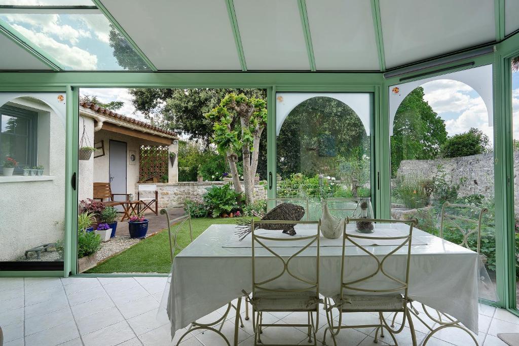 a conservatory with a table and chairs in it at Chambres Escale Pontilabienne in Pont-lʼAbbé-dʼArnoult