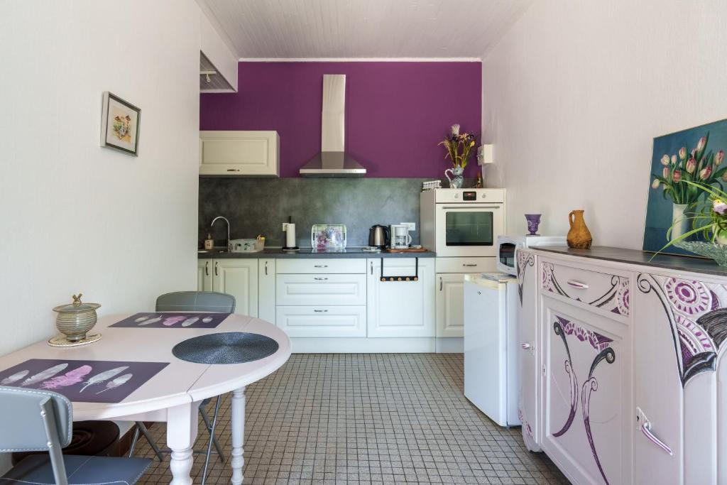 a kitchen with a table and a purple wall at Maison T2 - Le Boichot in Dole