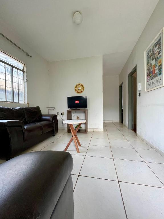 a living room with a couch and a tv at Casa Jardim Centro in Patos de Minas