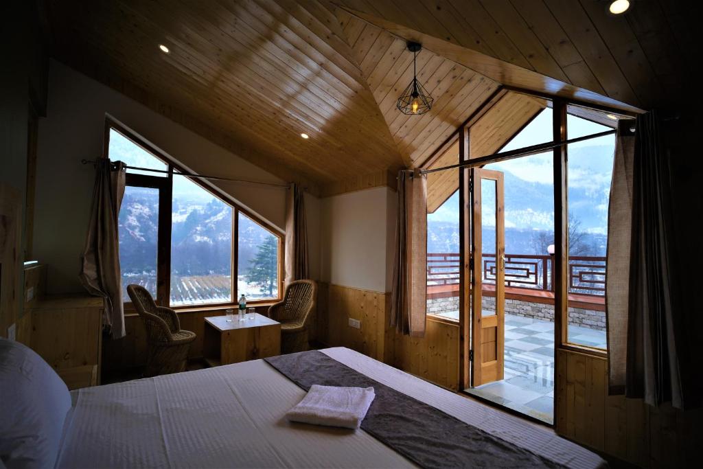 a bedroom with a bed and a large window at Mountainshack Riverside Stay & Cafe in Kulu