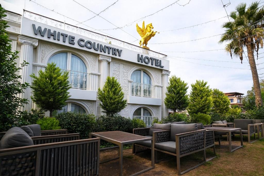a white country hotel with tables and chairs at White Country Villages Hotel in Antalya