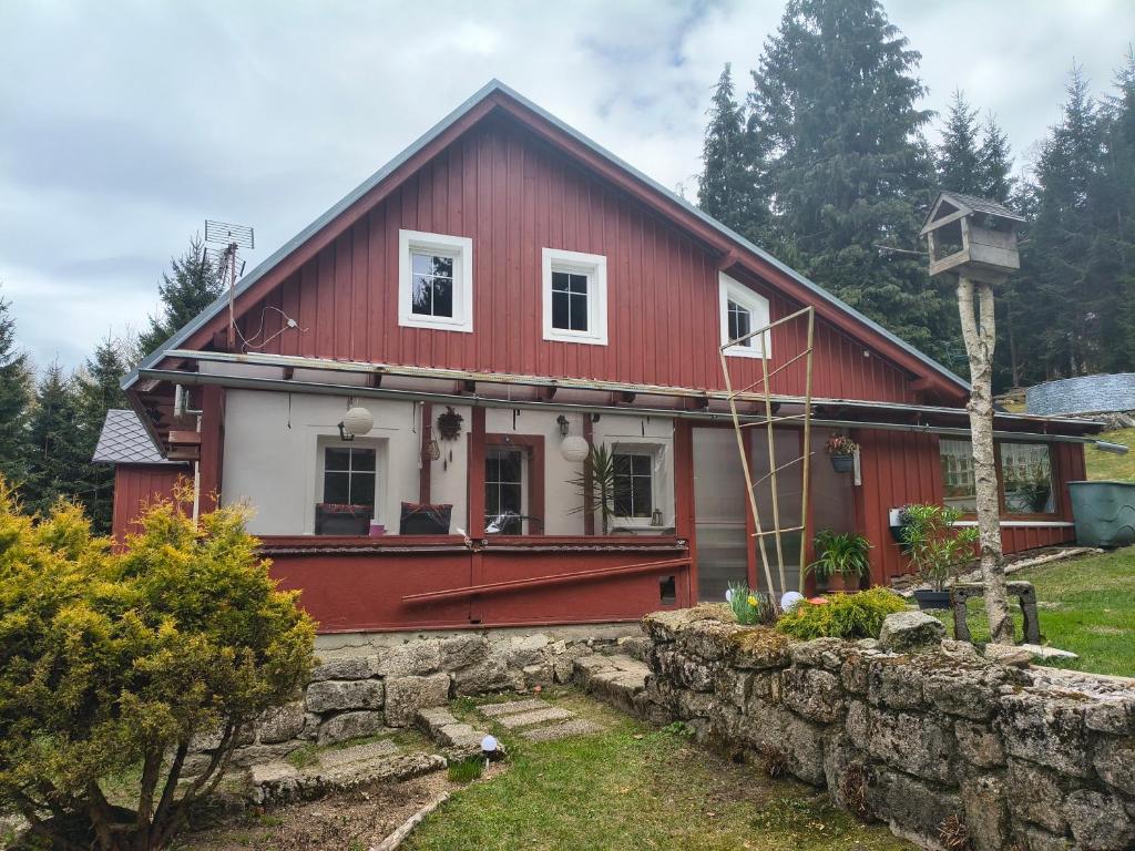 a red and white house with a stone wall at Chalupa pod smrky in Bedřichov