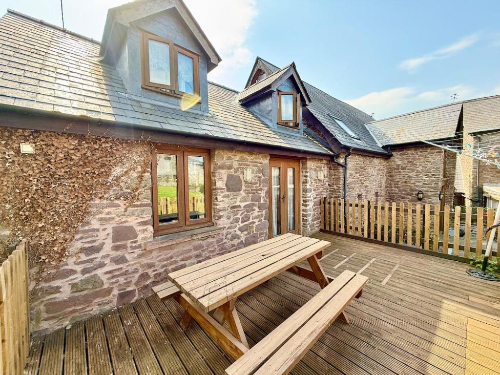 a wooden patio with a wooden bench on a wooden deck at Very spacious rural 2 bed barn sleeps 5 in Usk