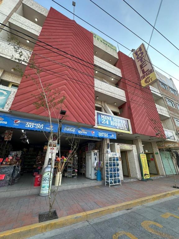 a building with a red roof on a city street at Hotel Topacio in San Juan de los Lagos