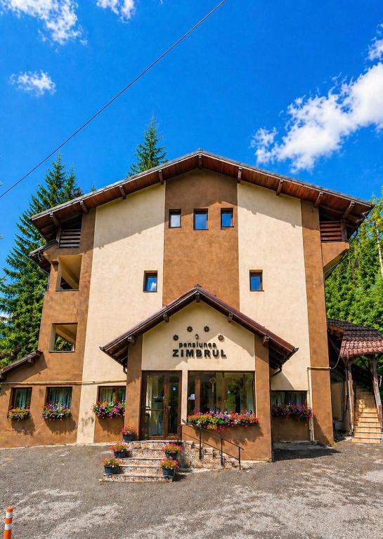 a large building with stairs and flowers in front of it at Pensiunea Zimbrul in Poiana Brasov