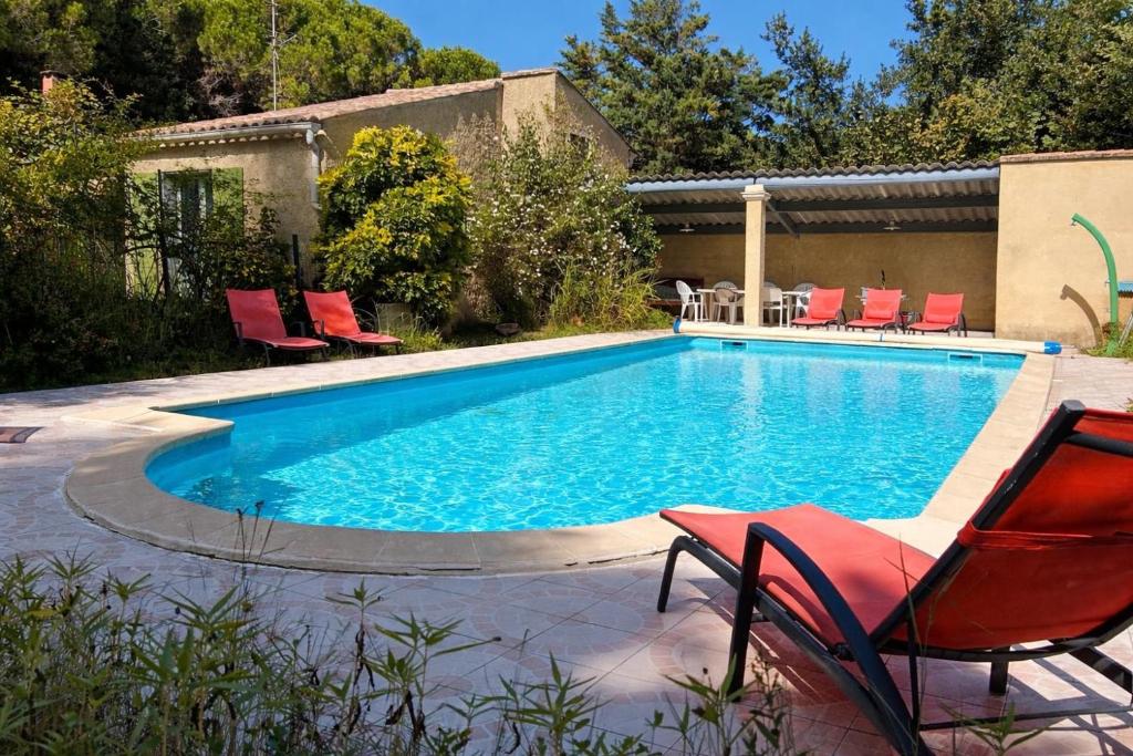 a swimming pool with red chairs next to at Villa La Marpierre in Mondragon