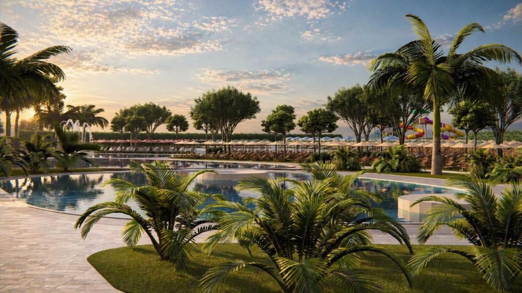 a resort swimming pool with palm trees in the background at Delta Open Air Resort in Porto Garibaldi