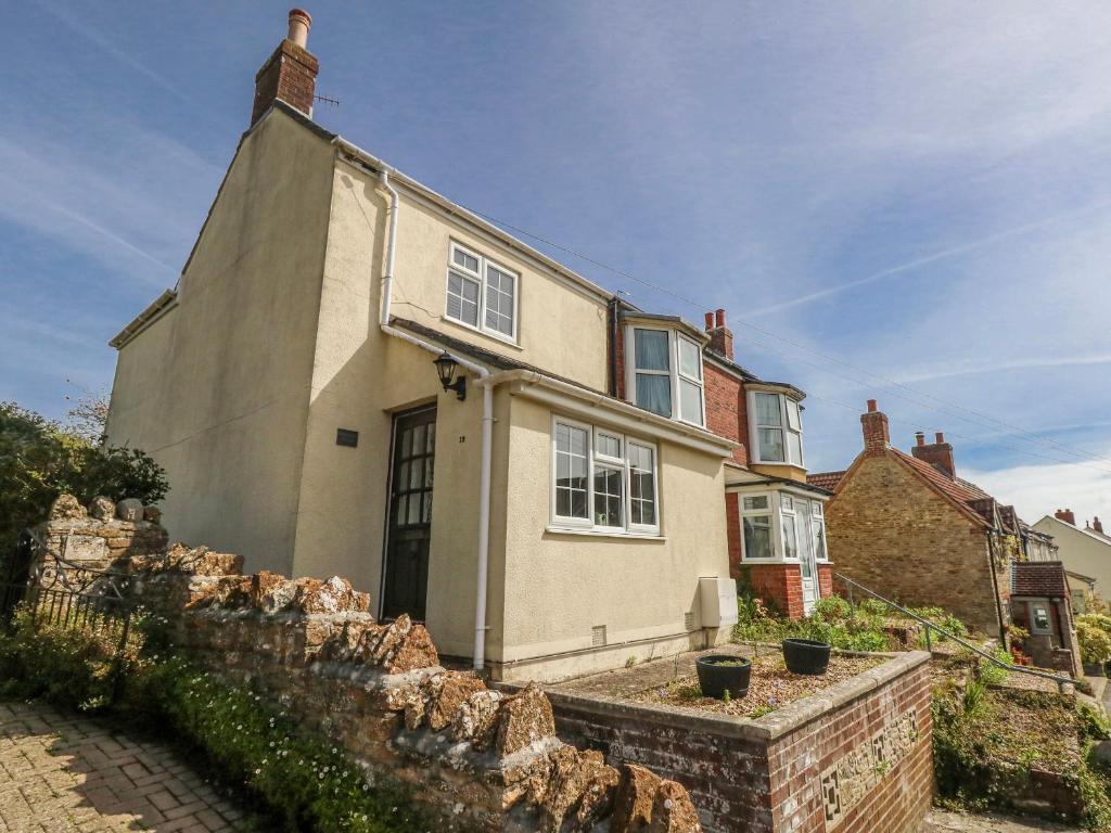 a house with a stone wall in front of it at September Cottage in Weymouth