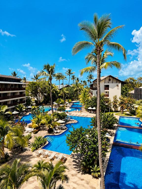 an aerial view of a resort pool with palm trees at Nannai Beira Mar, Flat Duplex em Muro Alto - Porto de Galinhas in Porto De Galinhas